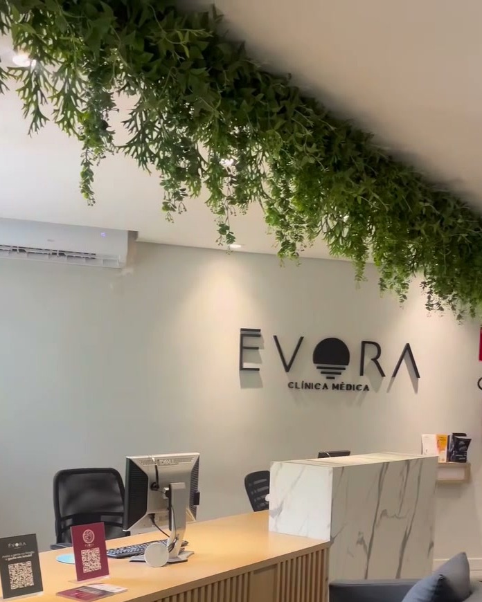 Recepção da Clínica Évora com o logo na parede e plantas